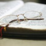 Close-up of eyeglasses atop an open Bible with colorful bookmarks, ideal for religious study themes.